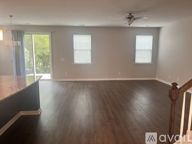 A spacious room with wooden floors and a ceiling fan.