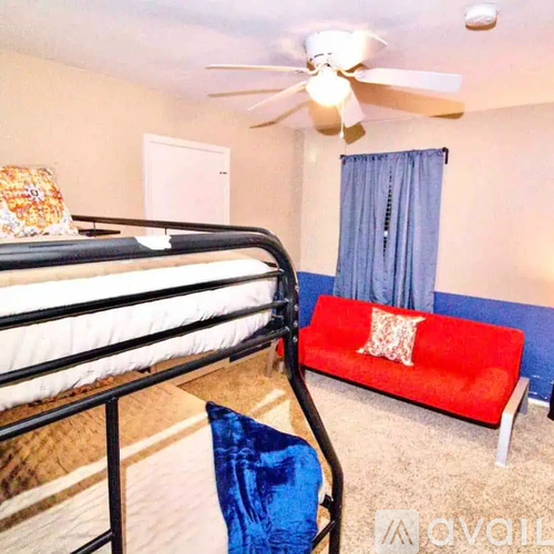 A bedroom with a red couch and a black metal bed frame.