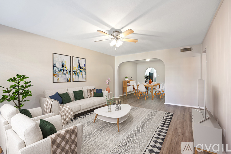 A living room with a white couch, a coffee table, and a ceiling fan.