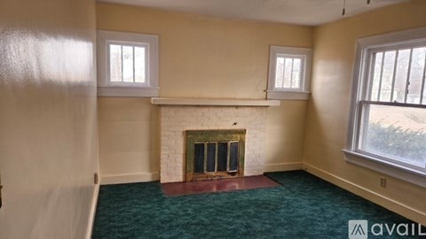 A room with a fireplace and two windows.