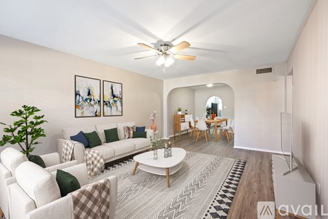 A living room with a white couch, a coffee table, and a ceiling fan.