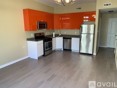 A kitchen with orange cabinets and a stainless steel refrigerator.