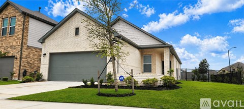 A house with a garage and a tree in front.