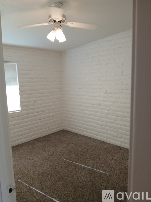 A room with a ceiling fan and a window with blinds.