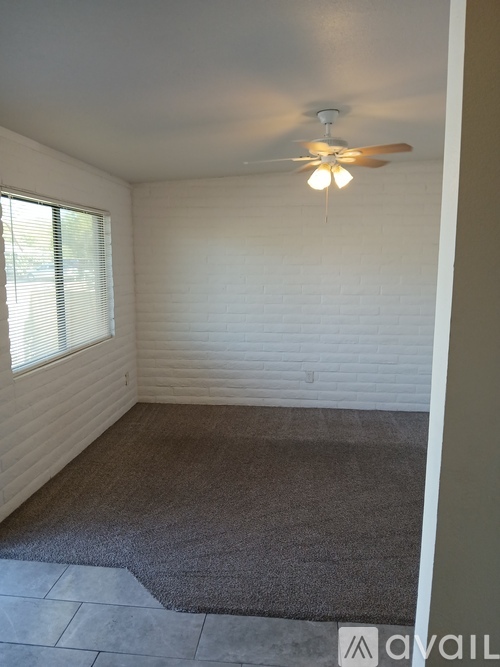 A room with a ceiling fan and a window with blinds.