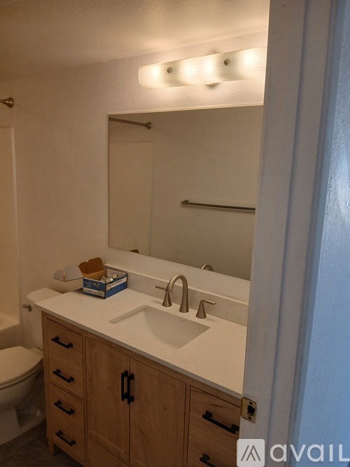A bathroom with a white counter top and a wooden cabinet.