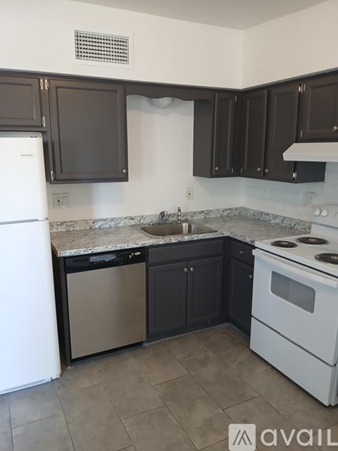 A kitchen with white appliances and dark brown cabinets.