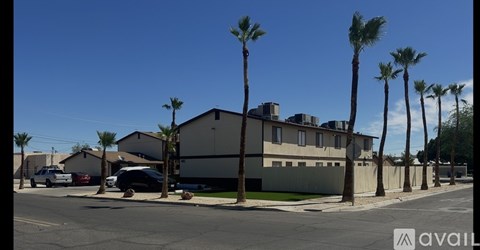 A street view with a building, cars, and palm trees.