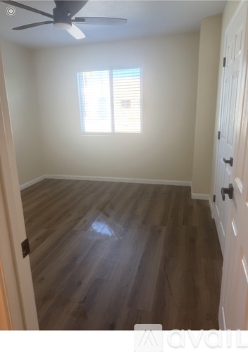 A room with wooden flooring and a window with blinds.