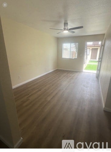 A room with a ceiling fan and wooden flooring.