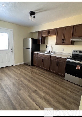 A kitchen with wooden floors and a black fridge.