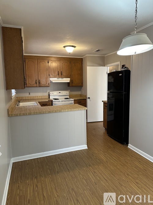 A kitchen with wooden cabinets and a black refrigerator.