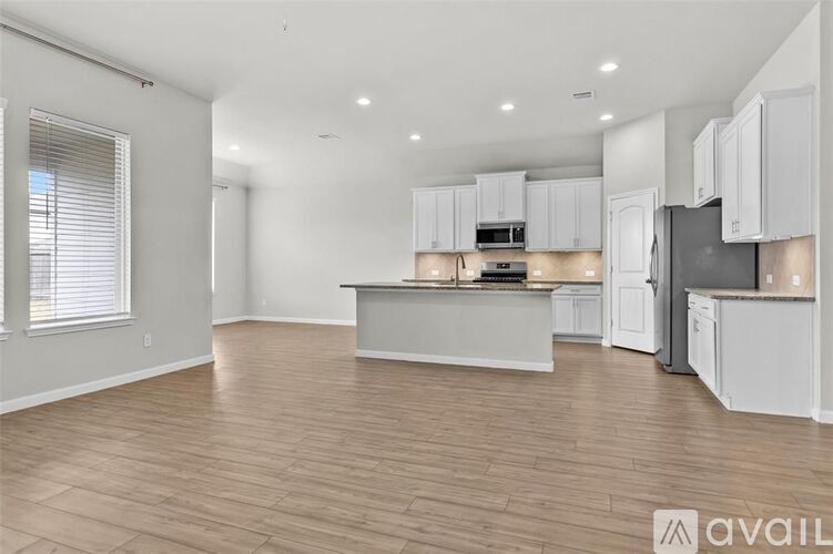 A kitchen with white cabinets and a wooden floor.