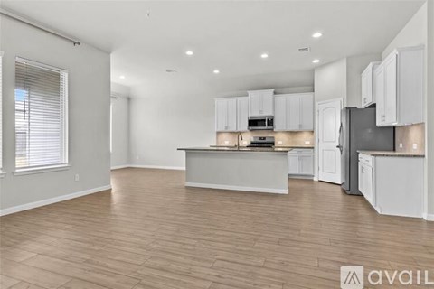 A kitchen with white cabinets and a wooden floor.