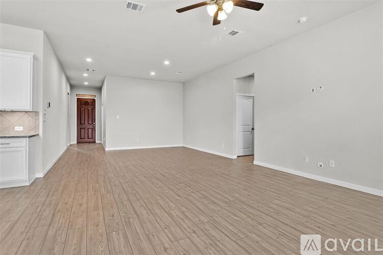 A spacious room with wooden flooring and a ceiling fan.