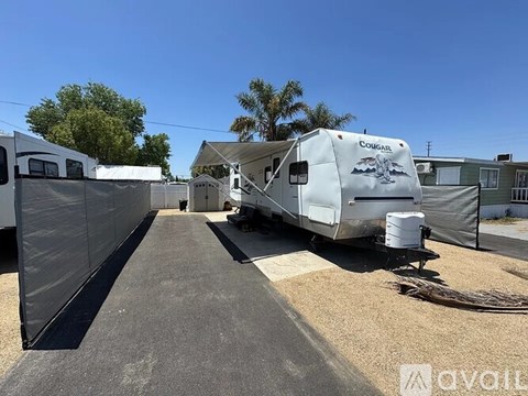 A white RV is parked in a lot with a black awning.