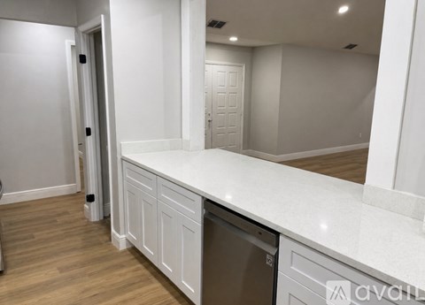 A kitchen with white cabinets and a dishwasher.