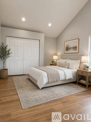 A bedroom with a large bed, a plant, and a framed picture on the wall.