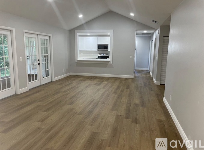 A spacious room with wooden flooring and a built-in cabinet with a microwave and oven.