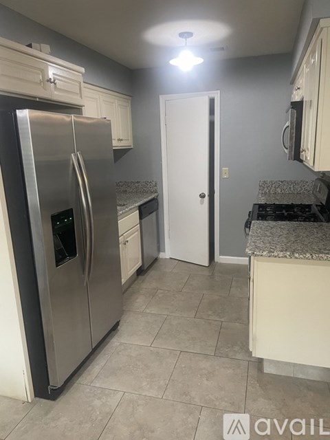 A kitchen with a stainless steel refrigerator and a white door.