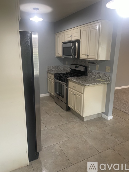 A kitchen with a black refrigerator and white cabinets.