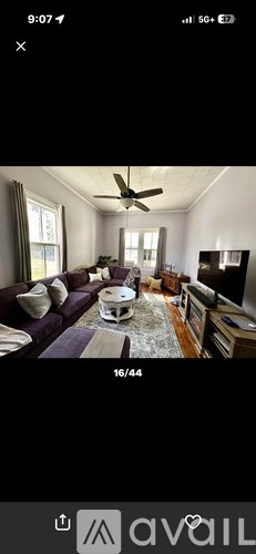A living room with a purple couch and a white coffee table.