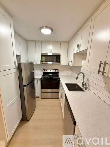 A kitchen with white cabinets and a stainless steel refrigerator.