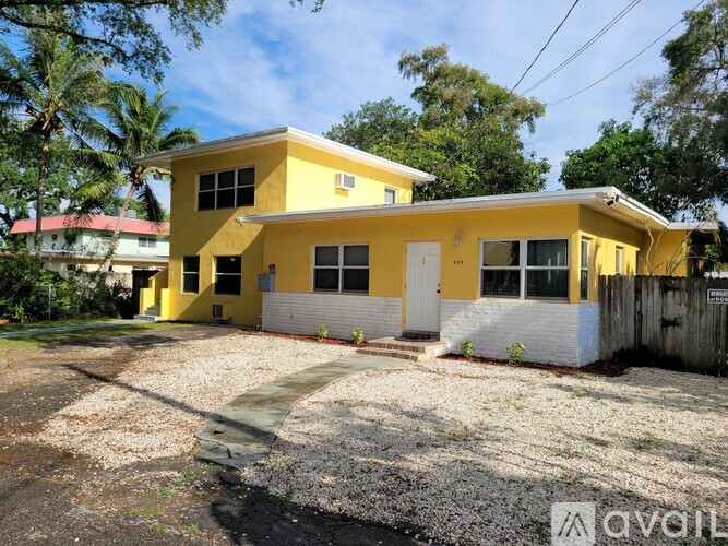 A yellow house with a white garage door is surrounded by trees.