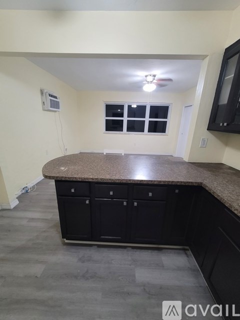 A kitchen with black cabinets and a granite countertop.