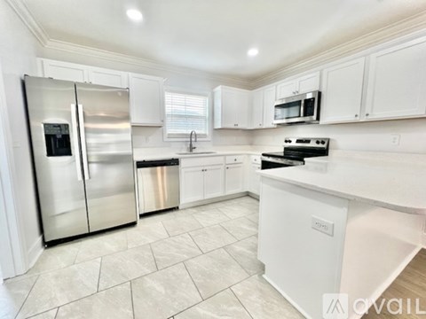 A kitchen with white cabinets and a stainless steel refrigerator.
