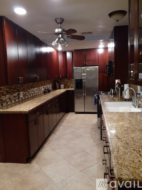A kitchen with brown cabinets and a marble countertop.