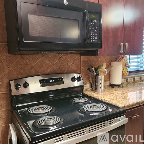 A black microwave oven is mounted above a stove top oven in a kitchen.