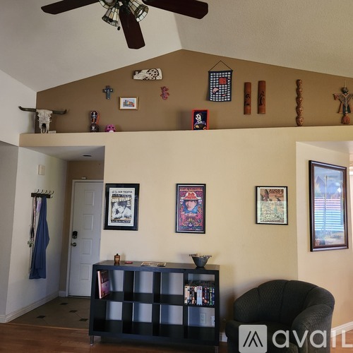 A living room with a ceiling fan and a black bookshelf.