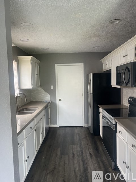 A kitchen with white cabinets and a black refrigerator.