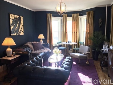 A living room with a black couch and a chandelier.