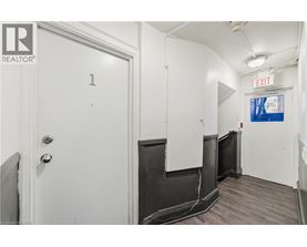 A white door with the number 1 on it is in a room with a white wall and a black door.