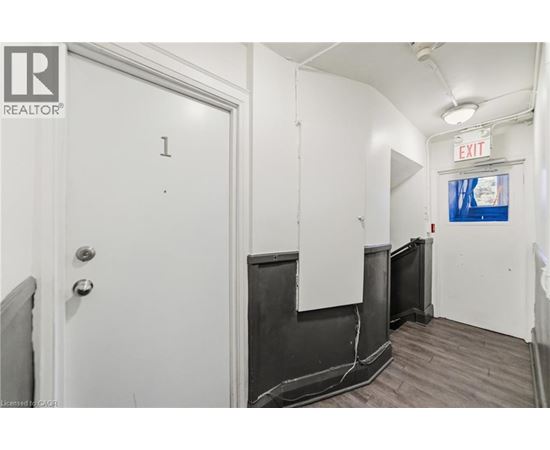 A white door with the number 1 on it is in a room with a white wall and a black door.