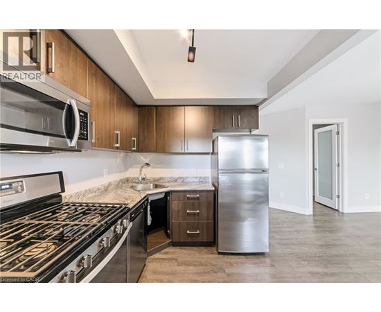 A modern kitchen with a stainless steel refrigerator, microwave, and oven.