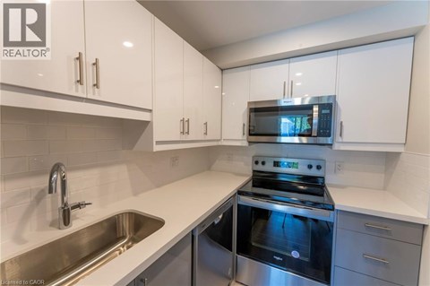 A modern kitchen with white cabinets and stainless steel appliances.