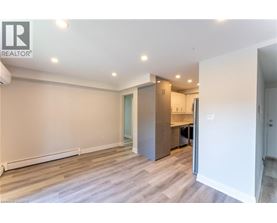 A spacious room with a kitchenette and a door leading to another room.