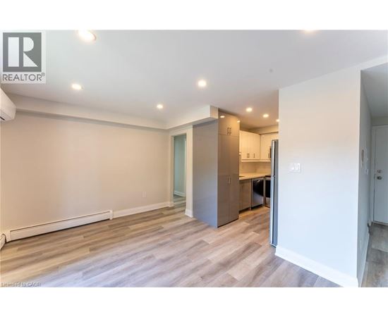 A spacious room with a kitchenette and a door leading to another room.
