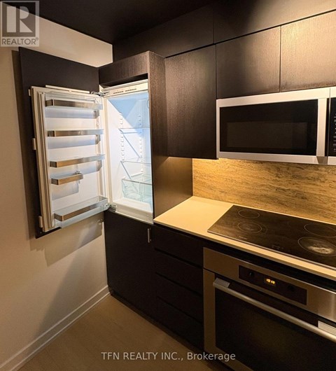 A kitchen with a stove top oven and a refrigerator with the door open.