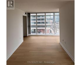A room with wooden flooring and a large window overlooking a cityscape.