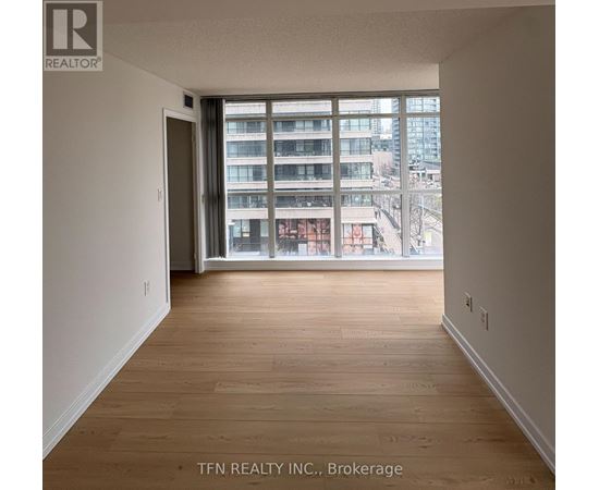 A room with wooden flooring and a large window overlooking a cityscape.