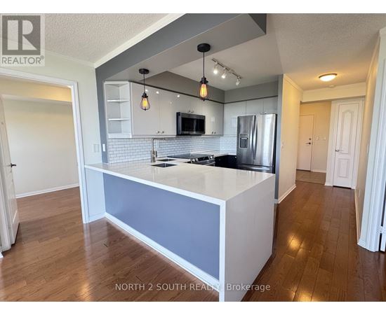 A kitchen with a refrigerator, microwave, and oven.