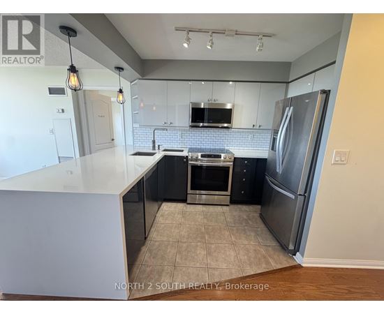 A kitchen with a refrigerator, oven, and microwave.