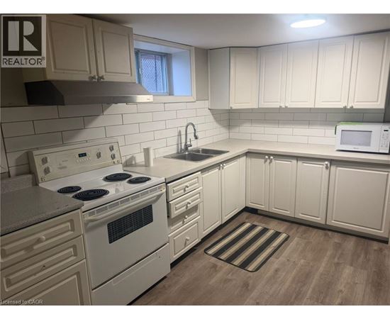 A kitchen with white cabinets and a white stove top oven.