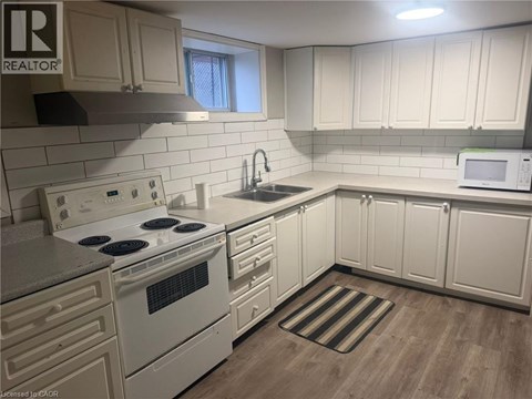 A kitchen with white cabinets and a white stove top oven.
