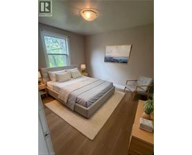 A bedroom with a bed, chair, and painting on the wall.