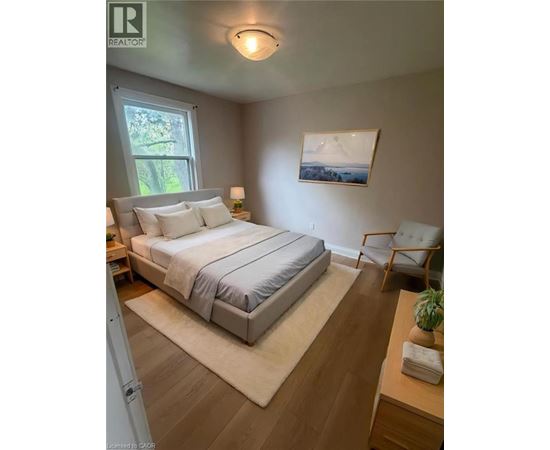 A bedroom with a bed, chair, and painting on the wall.